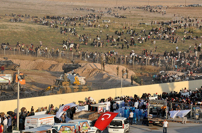Syrian refugees from Tel Abyad (foreground) line up at the border crossing as the others wait behind the fences to cross into Turkey at the Akcakale border gate in Sanliurfa province, Turkey, June 14, 2015 (Reuters Photo)