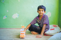 Ahmed Hamdo playing with toys in his scarcely furnished room. He stays with his brothers and sisters in a dilapidated house in İzmir.