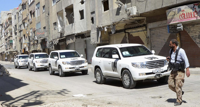 A member of the Free Syrian Army (FSA) passes near UN vehicles