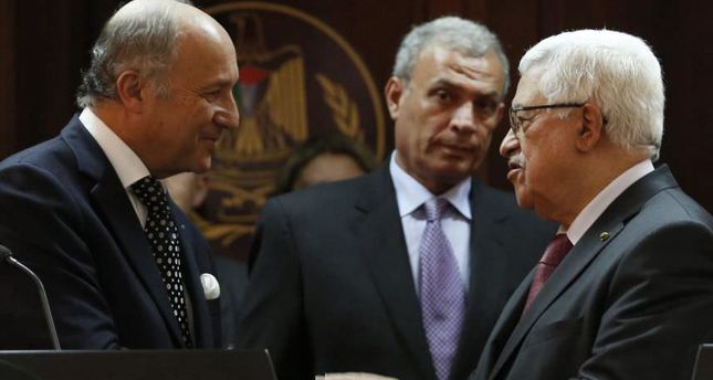 An archive photo from August 24, 2013, shows Palestinian President Mahmoud Abbas, right, and Frances Foreign Minister Laurent Fabius shaking hands following their meeting in Ramallah