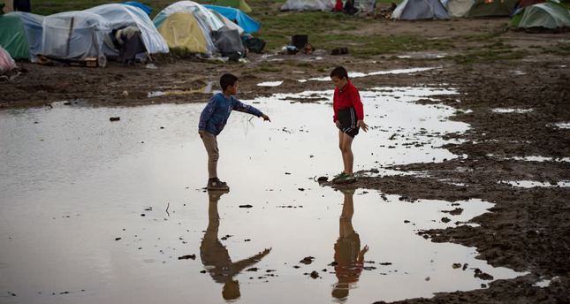Two boys standing in a puddle at a makeshift camp for migrants and refugees at the Greek-Macedonian border near the village of Idomeni.